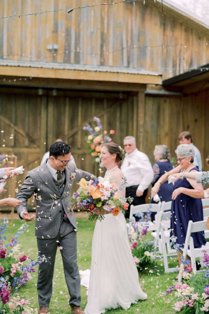 Guests tossing flower petals at bride and groom at ceremony exit